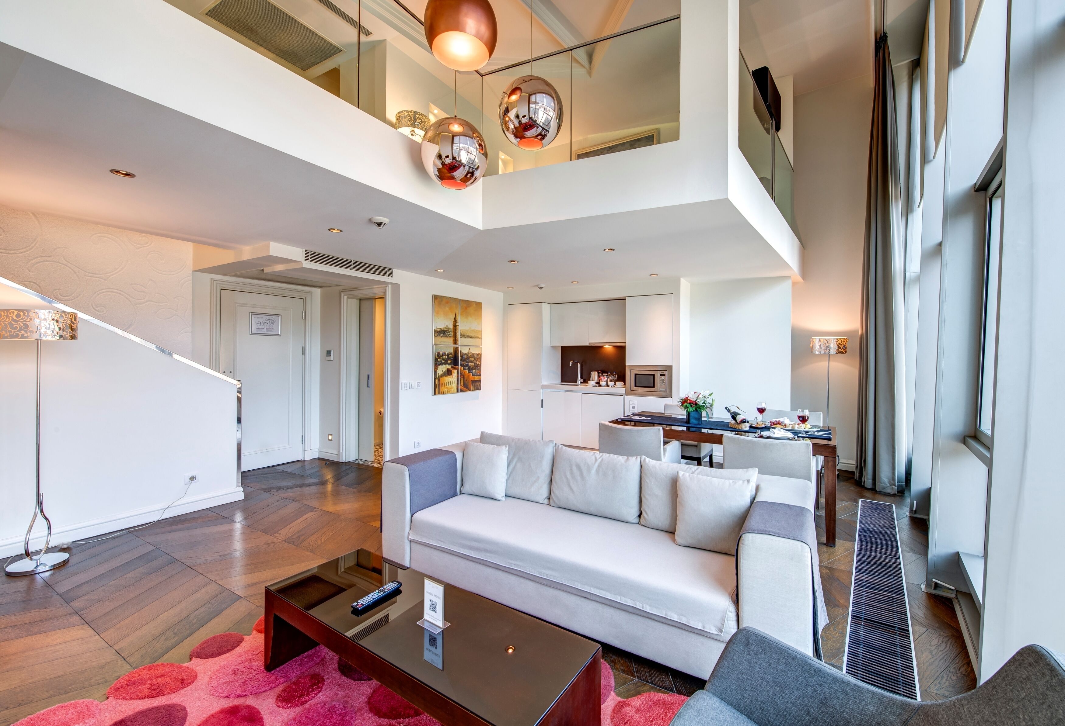 A modern living room with a sofa, a coffee table, and a dining area with a kitchen in the background.