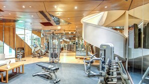Ein modernes Fitnessstudio mit verschiedenen Trainingsgeräten, darunter Laufbänder, Kraftgeräte und Kurzhanteln.