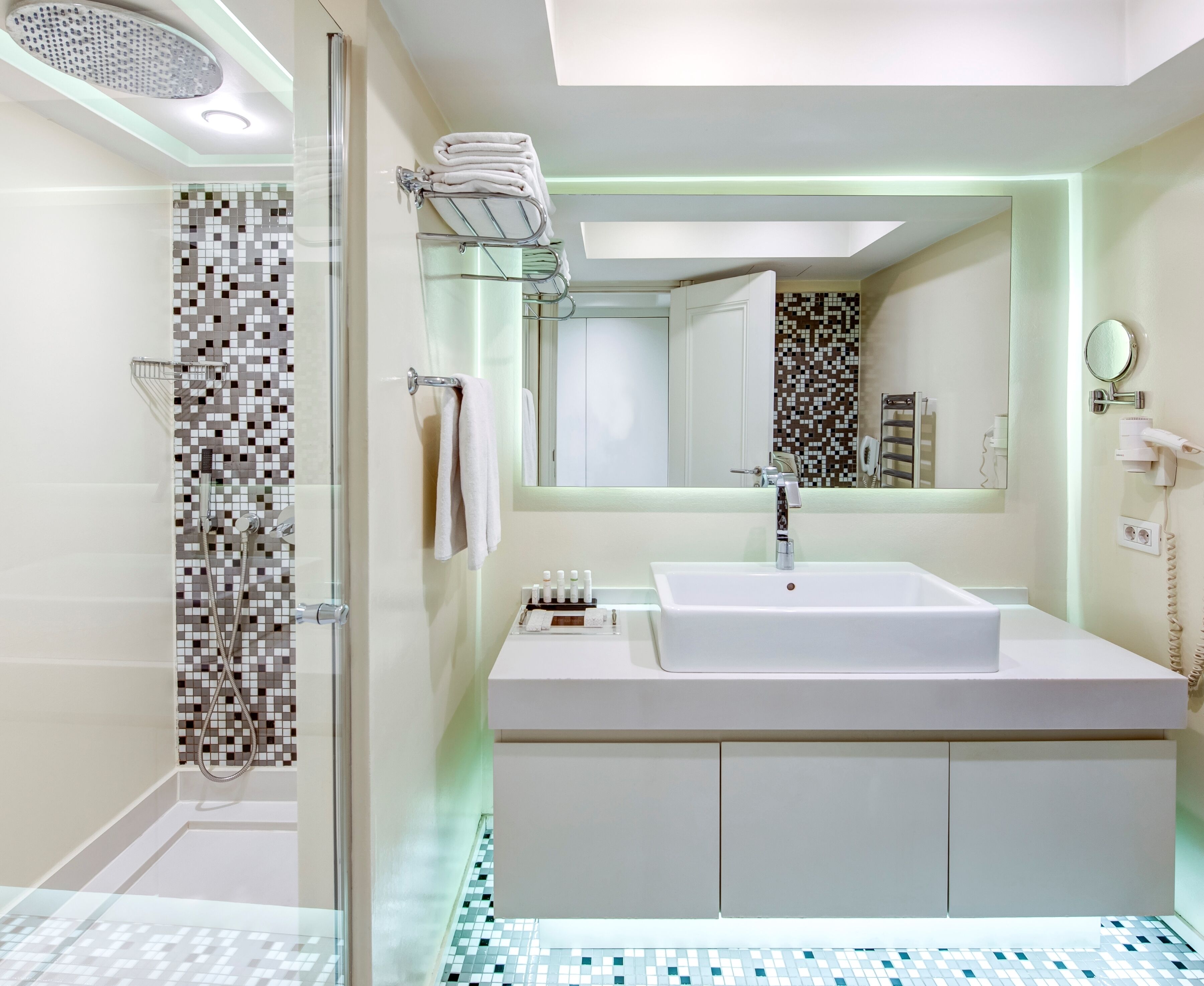 A modern bathroom with a glass-enclosed shower, a white sink, and a mirror above it.