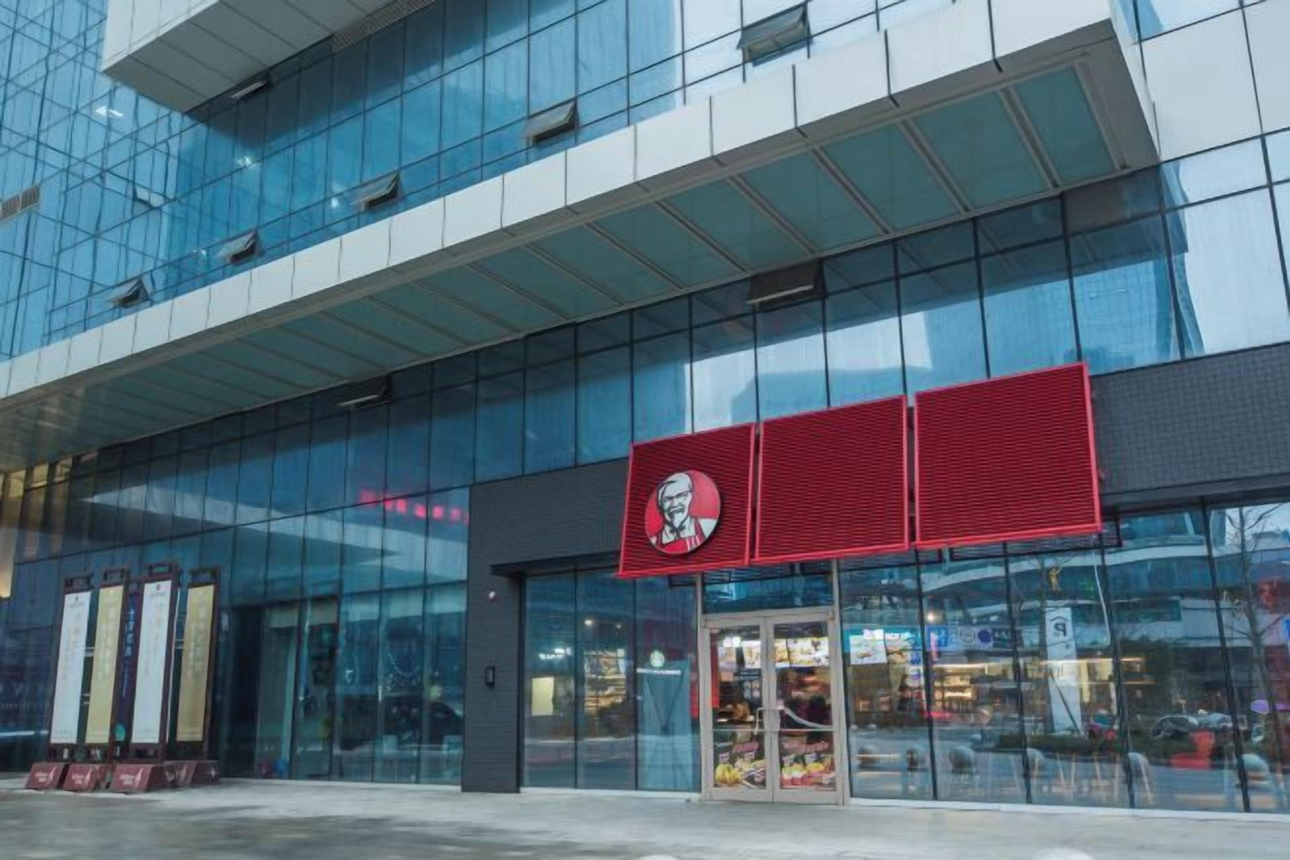 A modern building with a glass facade and a prominent red sign.