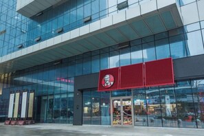 A modern building with a glass facade and a prominent red sign. - East Harbour Hotel (Ningbo)