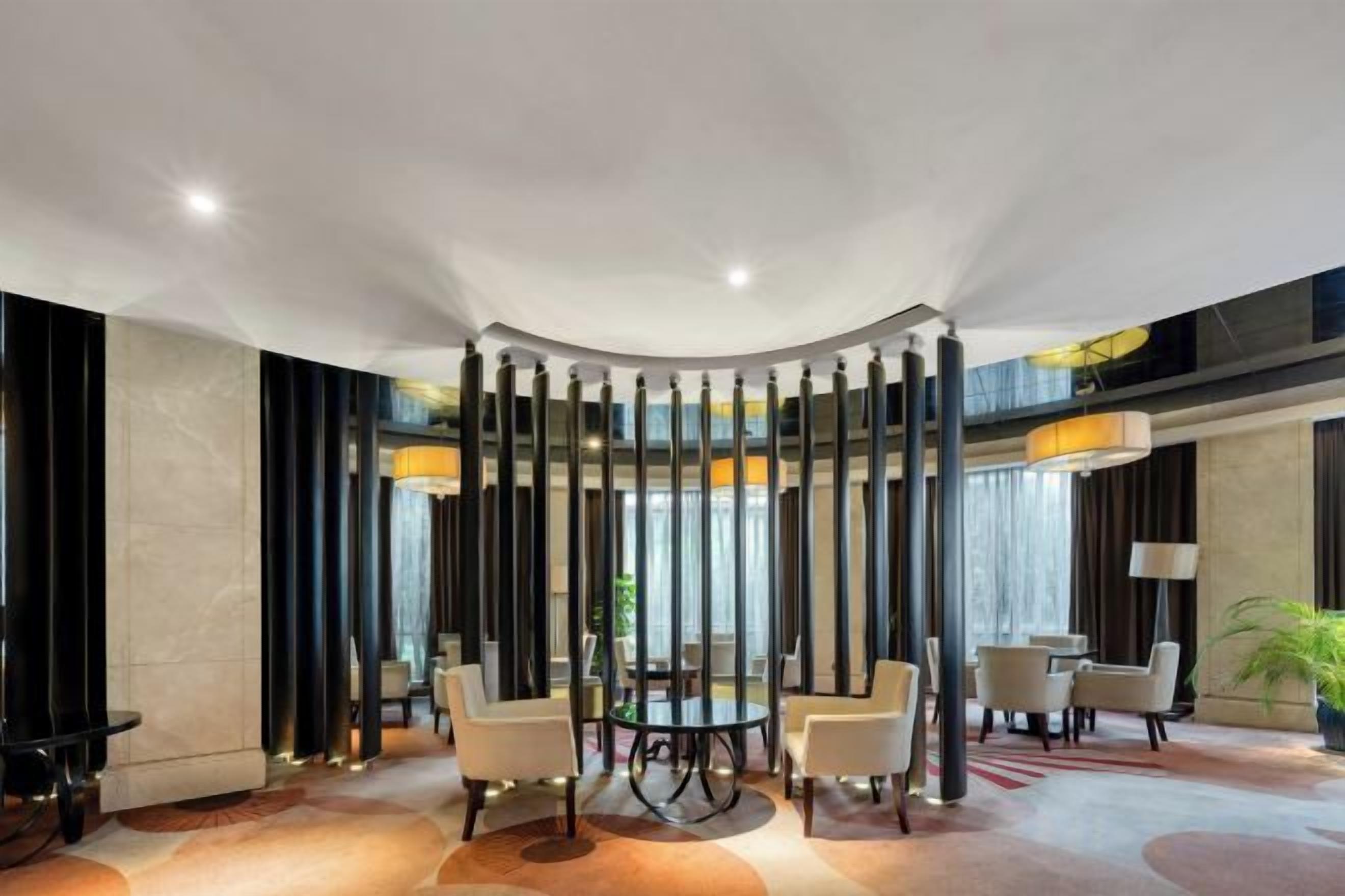 A modern hotel lobby with a round table, seating area, and a decorative column structure.