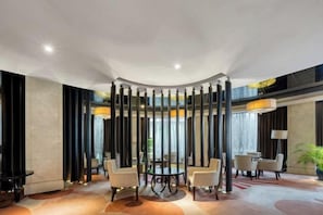 A modern hotel lobby with a round table, seating area, and a decorative column structure. - East Harbour Hotel (Ningbo)