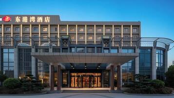 Un hotel con fachada moderna, un acceso cubierto y un cielo despejado.