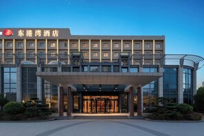 A hotel with a modern facade, a covered entrance, and a clear sky. - East Harbour Hotel (Ningbo)
