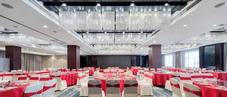 A banquet hall with rows of tables, chairs, and a chandelier.