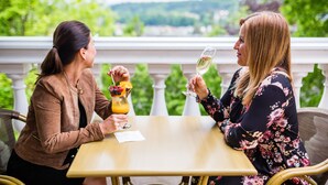 Dos personas sentadas en una mesa al aire libre con una vista panorámica de fondo.