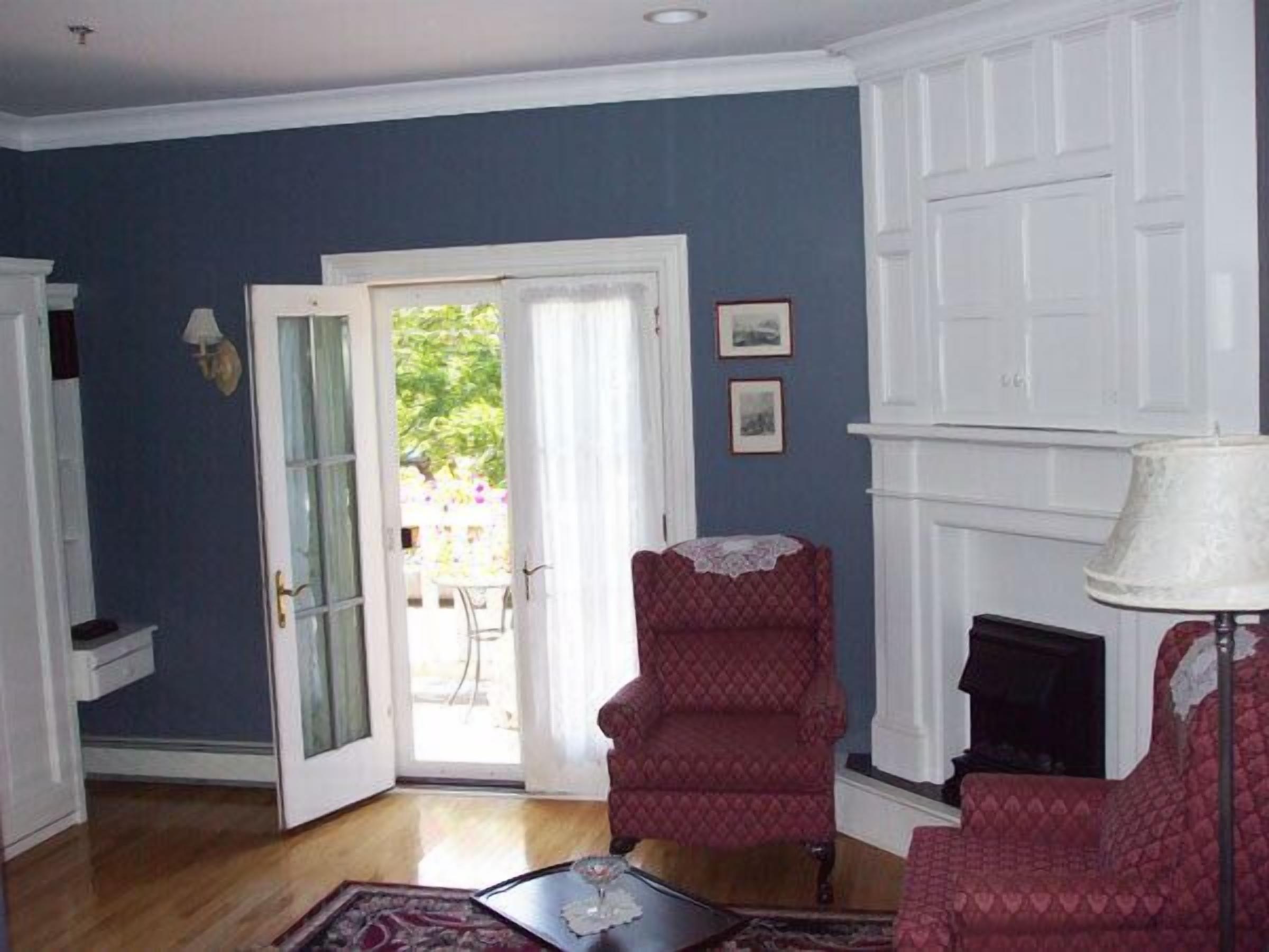 A room with a blue wall, a white fireplace, and a red armchair.