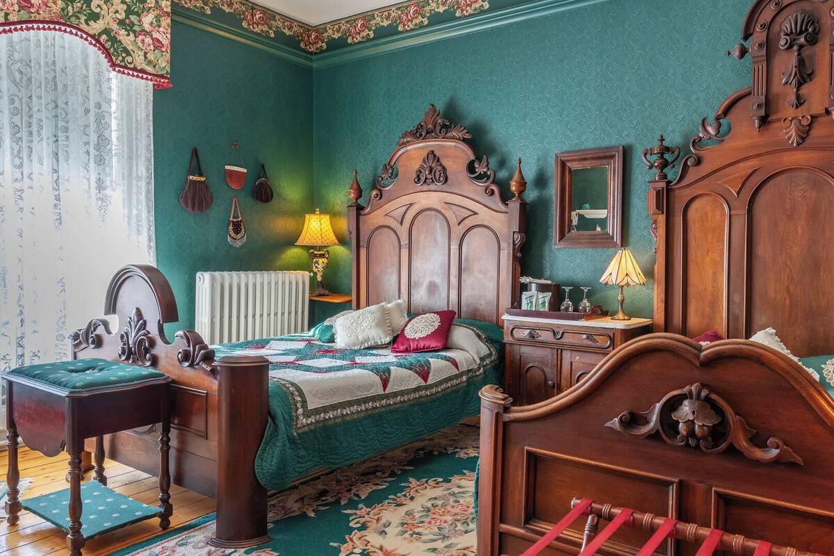 Un dormitorio tradicional con una cama de madera grande, dos mesitas de noche, un aparador y un espejo.
