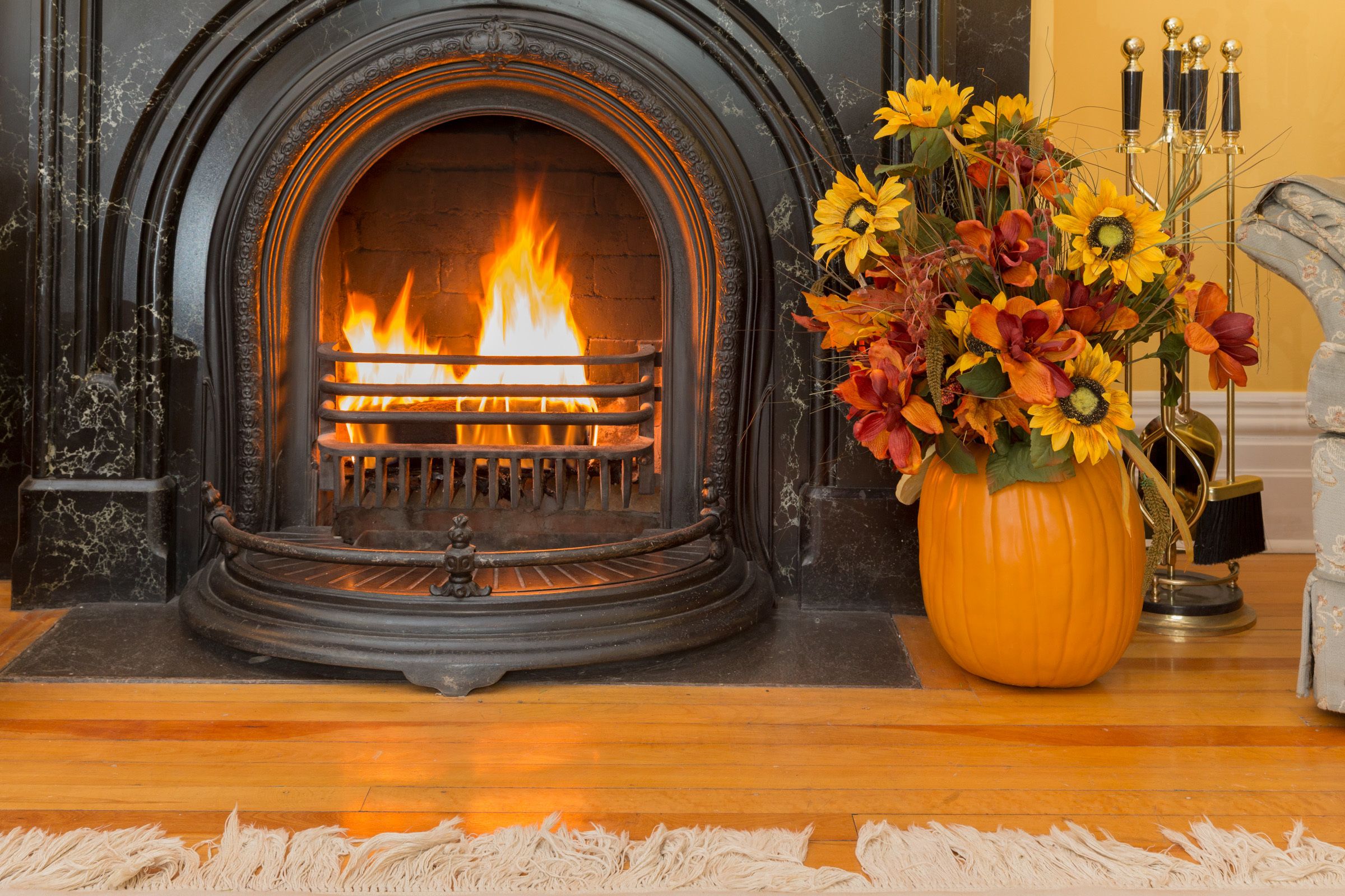 A fireplace with a fire, a large vase with flowers, and a candle holder.