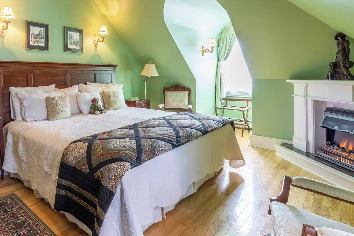 Un dormitorio con una cama grande, cabecera de madera, chimenea y una escalera.