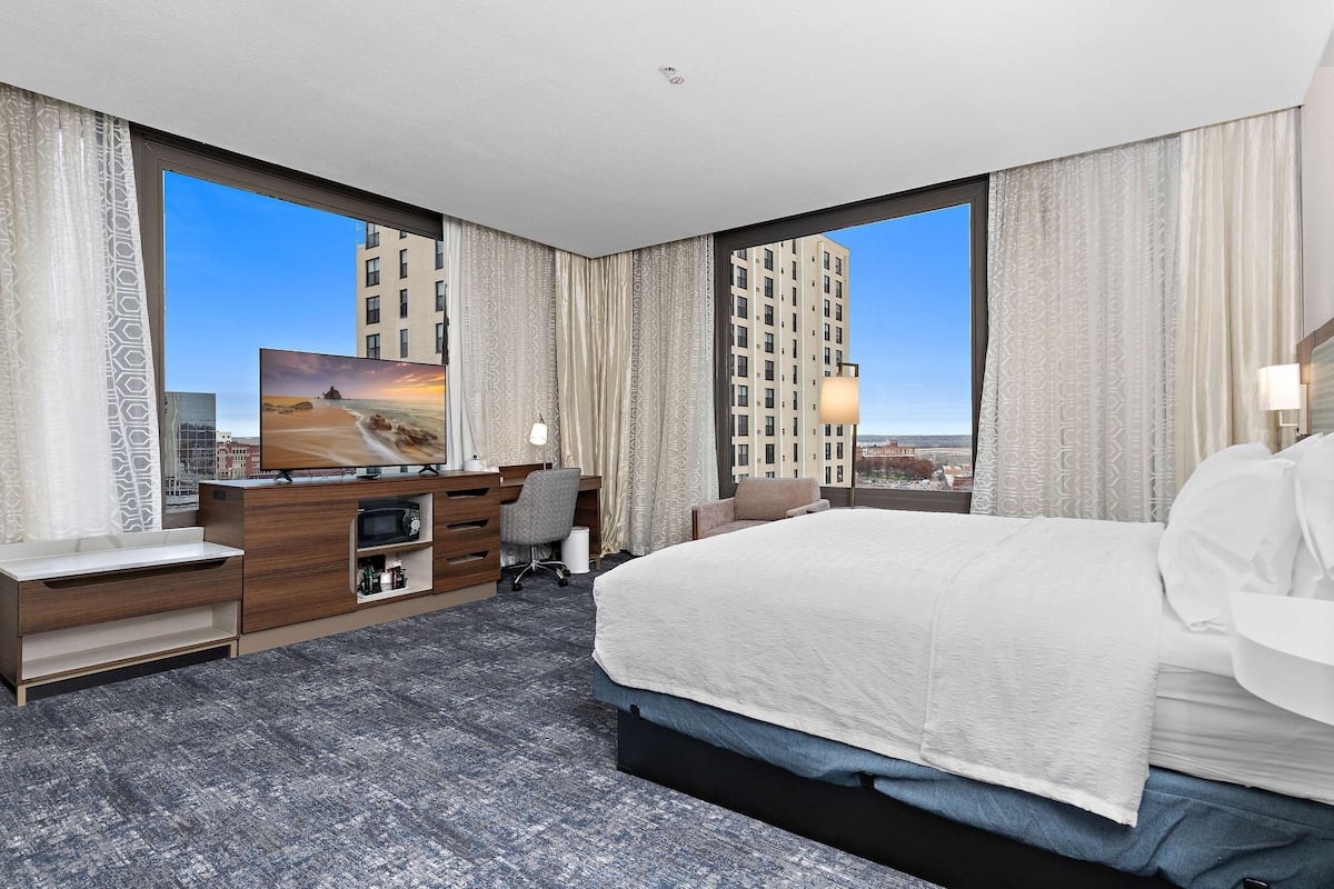 Une chambre d’hôtel moderne équipée d’un grand lit, d’un bureau avec un ordinateur, d’une chaise et d’un téléviseur.