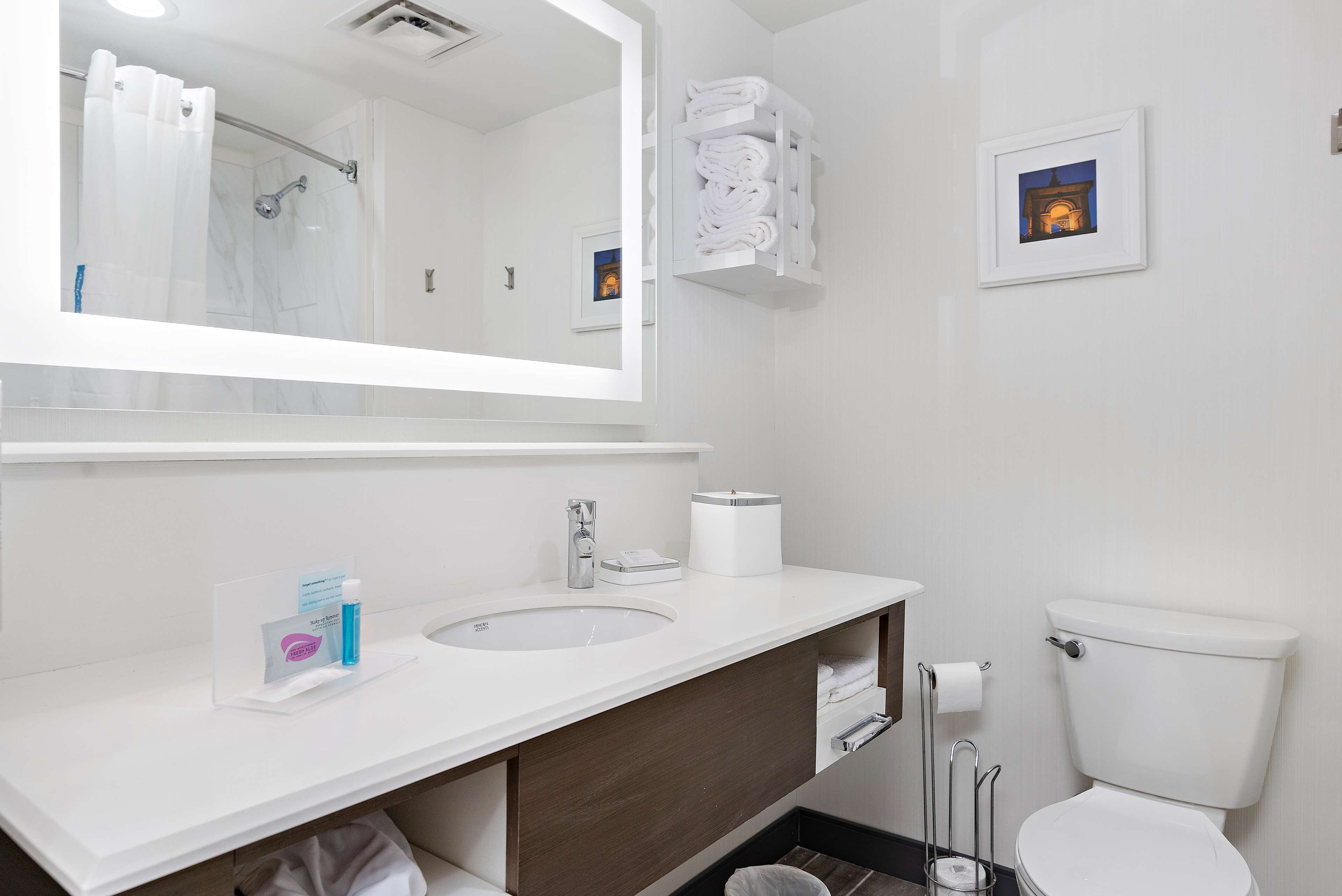 Un bagno moderno con uno specchio grande, un lavandino, un water e un portascopino.