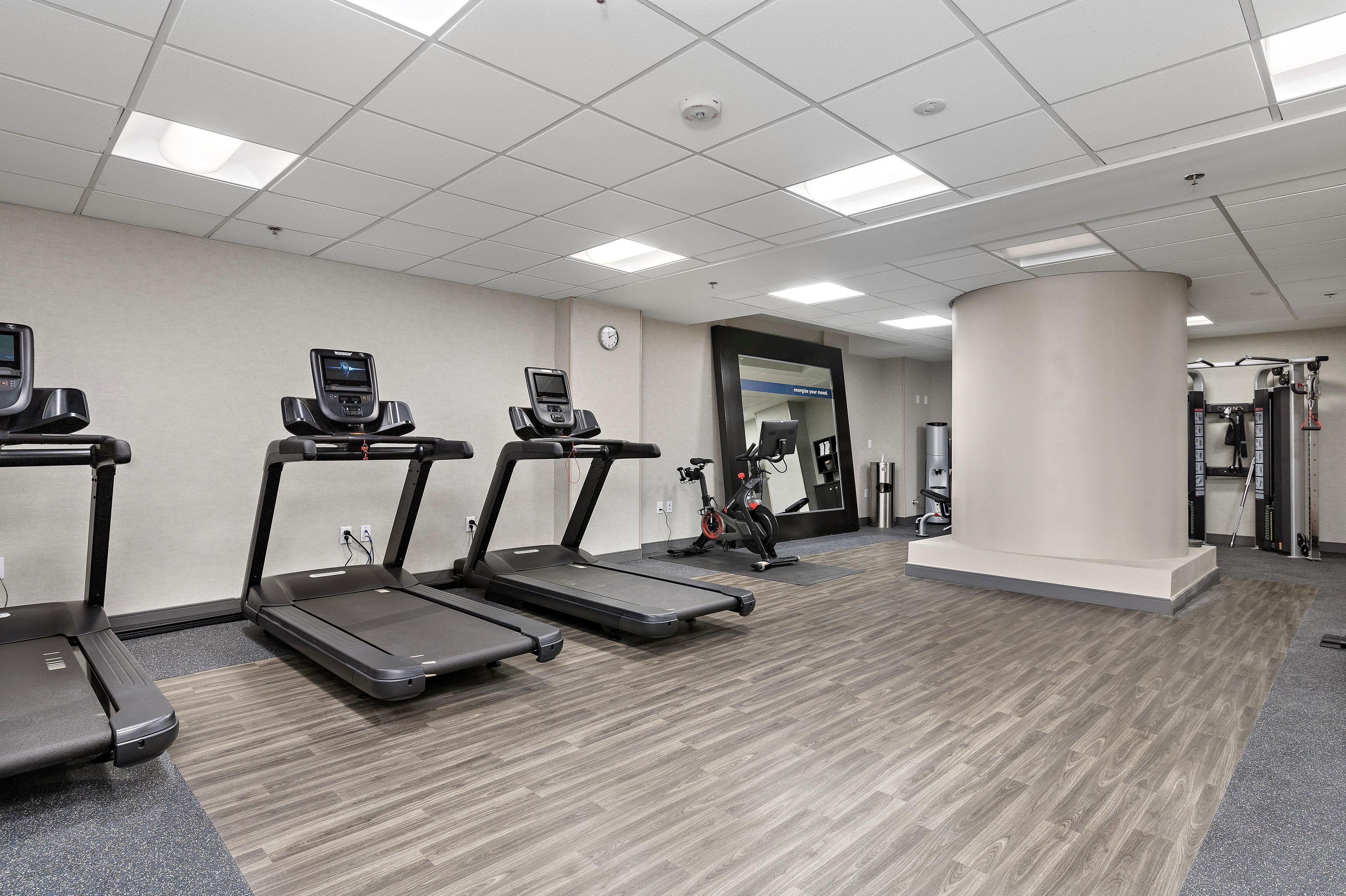 A fitness center with treadmills, a stationary bike, and a mirror.