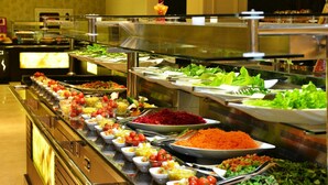 Un buffet proposant une variété de plats, notamment des salades, des fruits et des légumes.