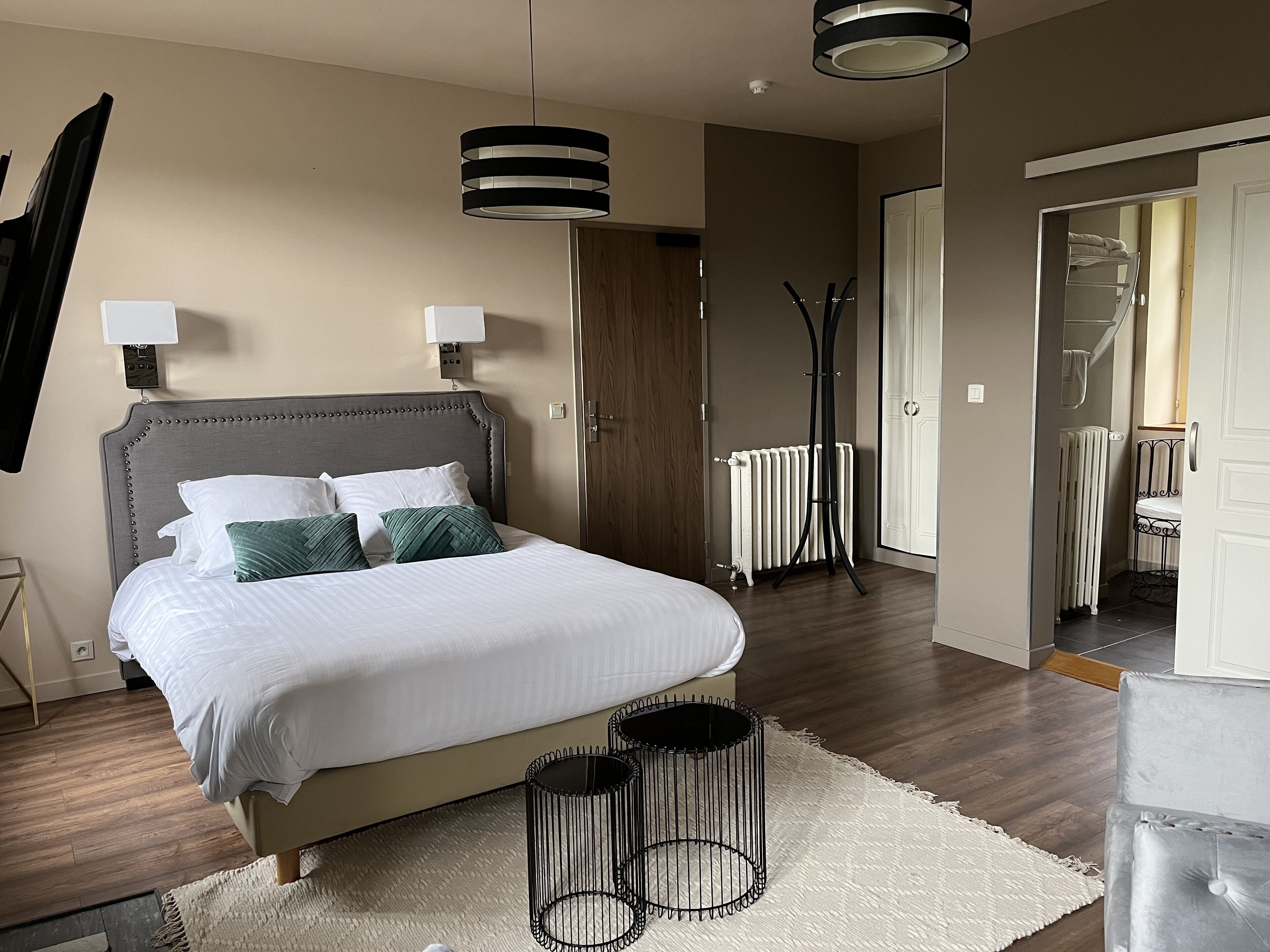A neatly arranged bedroom with a bed, bedside lamps, a radiator, and a wardrobe.