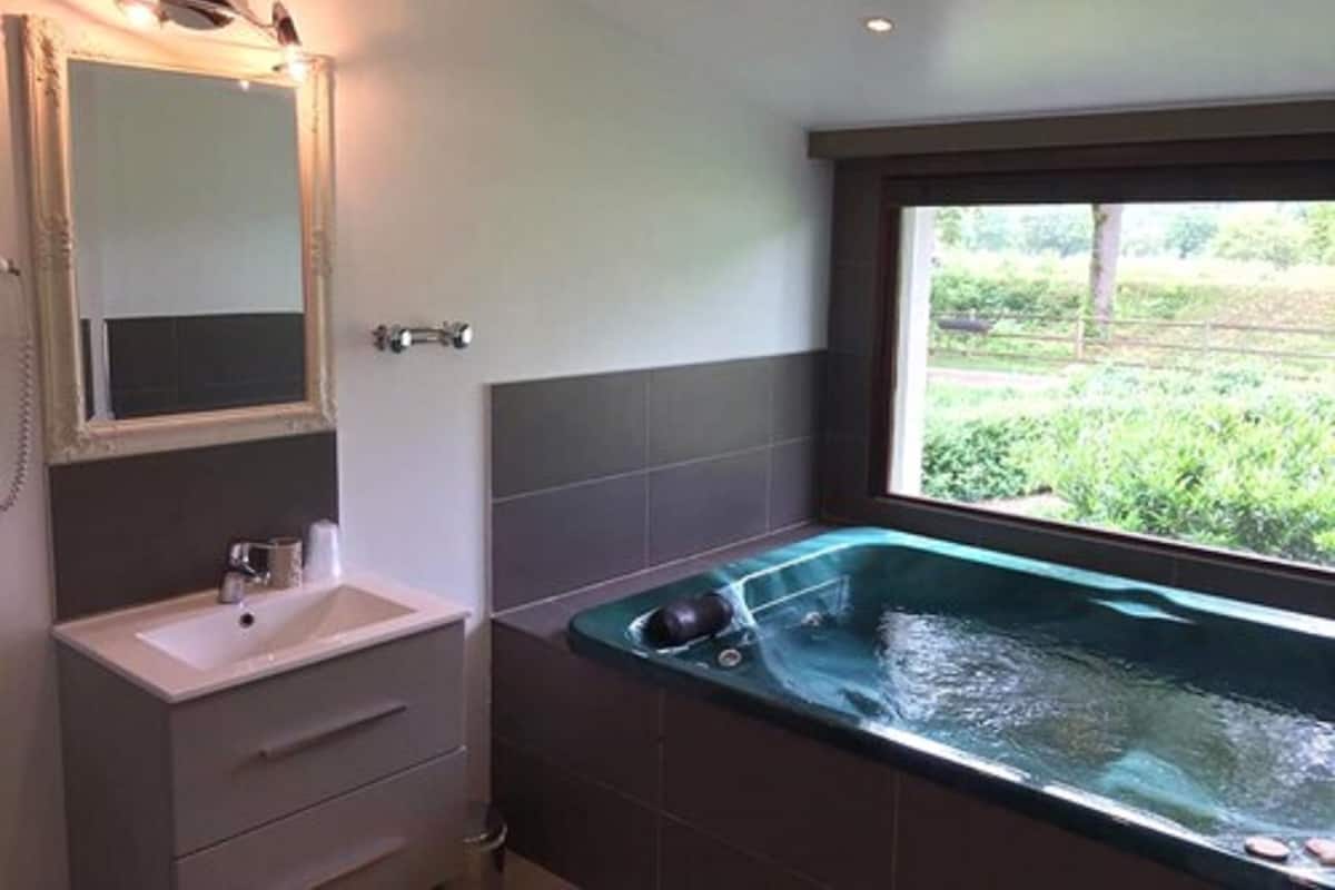A modern bathroom with a large bathtub, a sink, and a mirror.