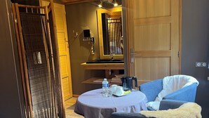 A cozy room with a wooden ceiling, a round table with a chair, a bed, and a large mirror. - Hôtel de la Vinaigrerie (Joinville)
