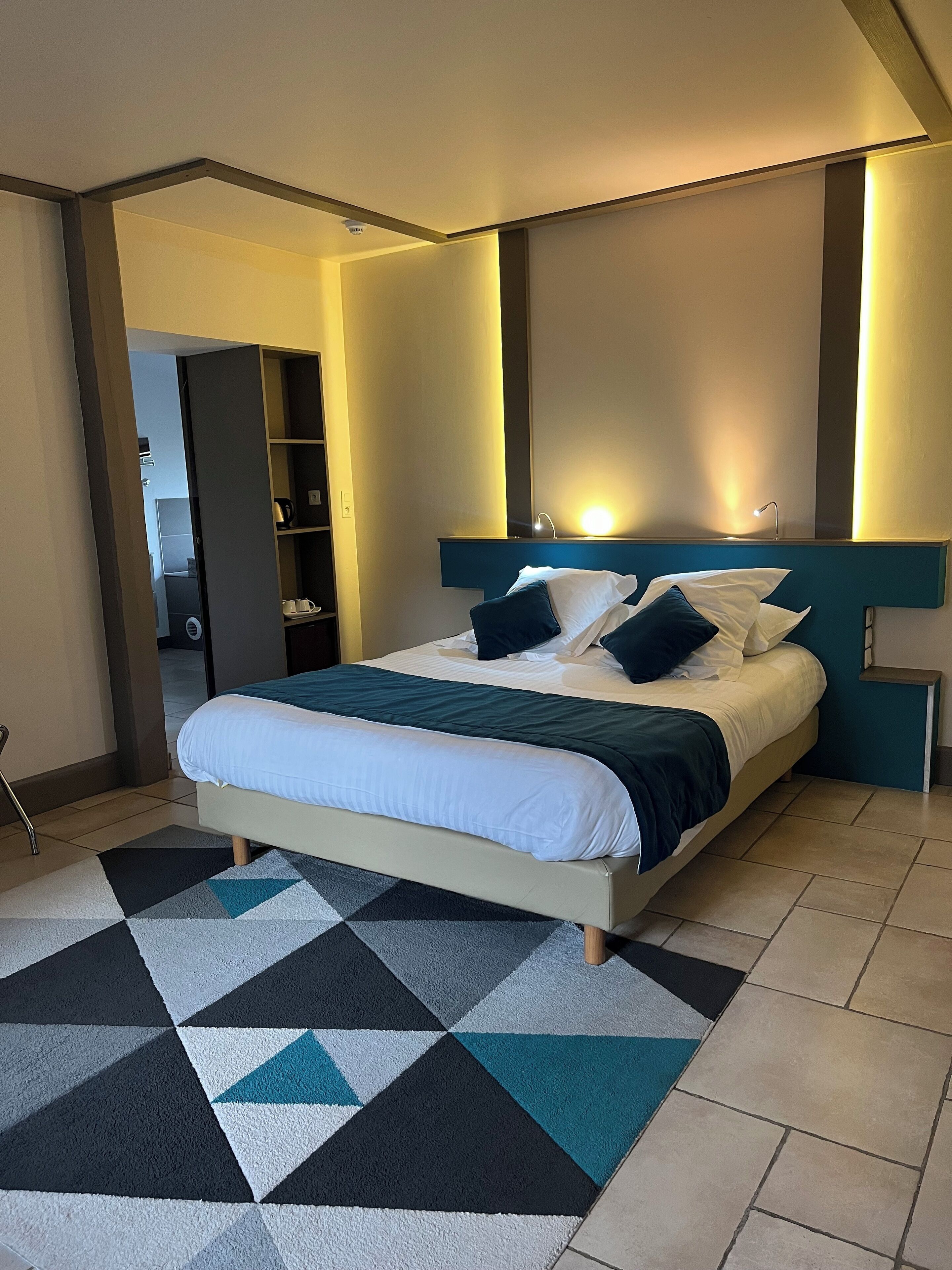 Un dormitorio moderno con cama, alfombra de diseño geométrico y mesita de noche.