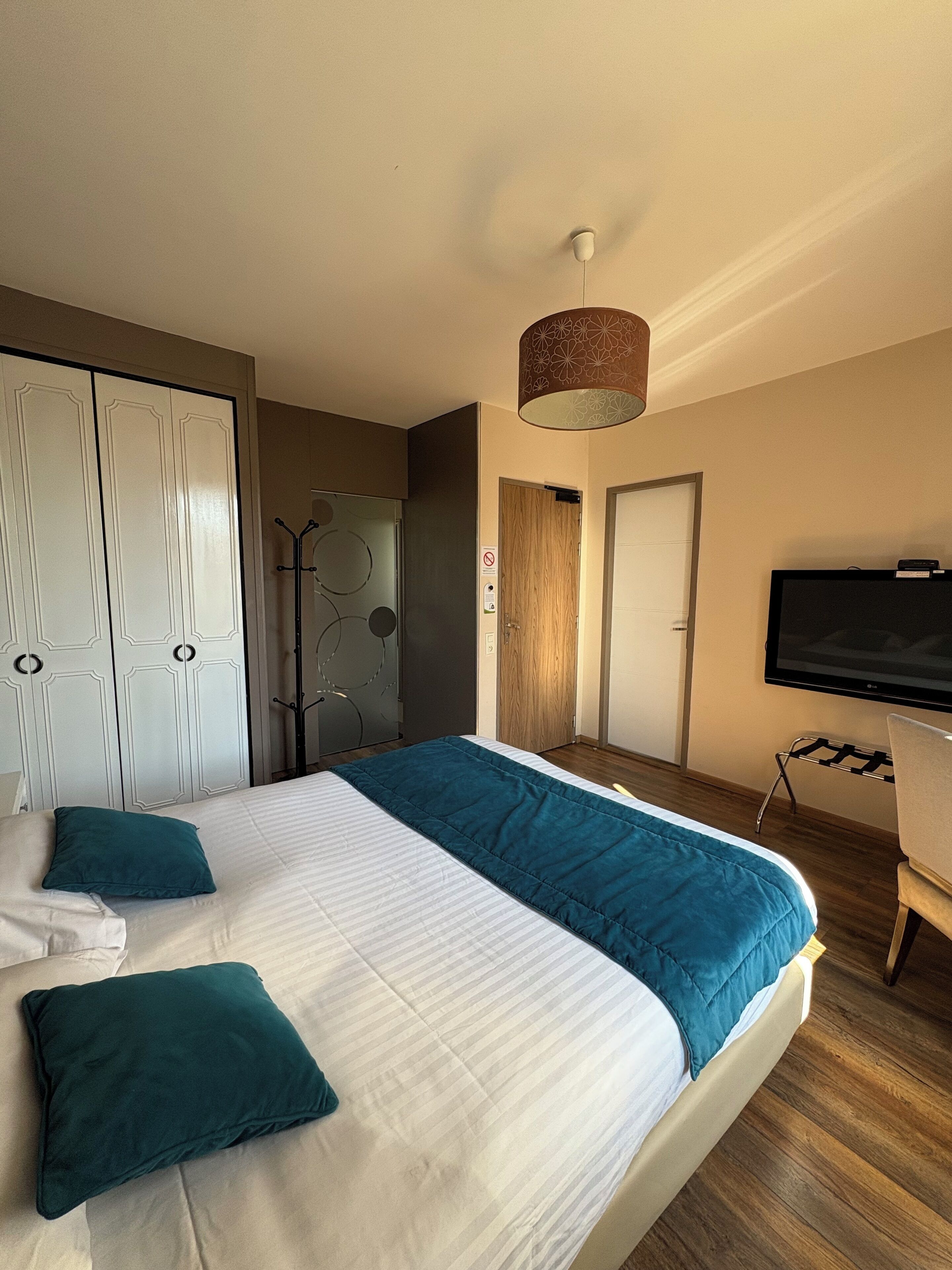 Ein Hotelzimmer mit einem großen Bett, einem Fernseher und einem Kleiderschrank.