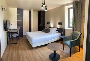 Ein modernes Hotelzimmer mit einem großen Bett, einem Schreibtisch, einem Stuhl und einem kleinen runden Tisch.