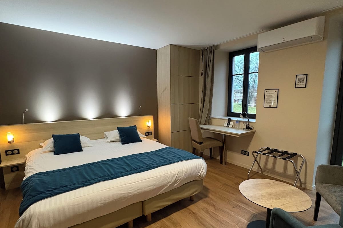 A modern hotel room with a large bed, a desk, and a chair.