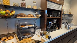 A modern kitchen with a variety of baked goods, including croissants and bread, displayed on shelves and counters. - Hôtel de la Vinaigrerie (Joinville)