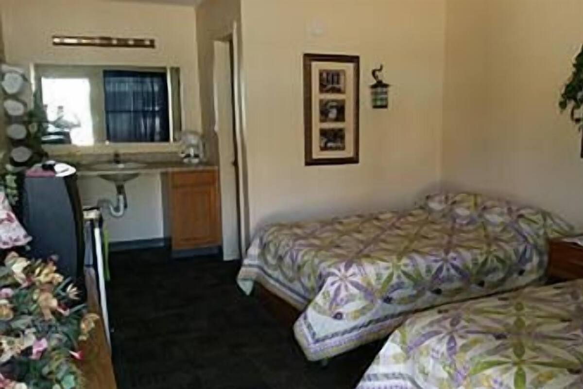 Una habitación pequeña y funcional con dos camas, un lavamanos y un espejo.
