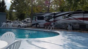 A swimming pool with adjacent RVs and a table with chairs. - Taneycomo Lakefront Resort (Branson)