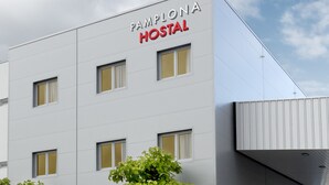 Un edificio moderno con un cartel que dice "Pamplona Hostel" y un acceso cubierto.
