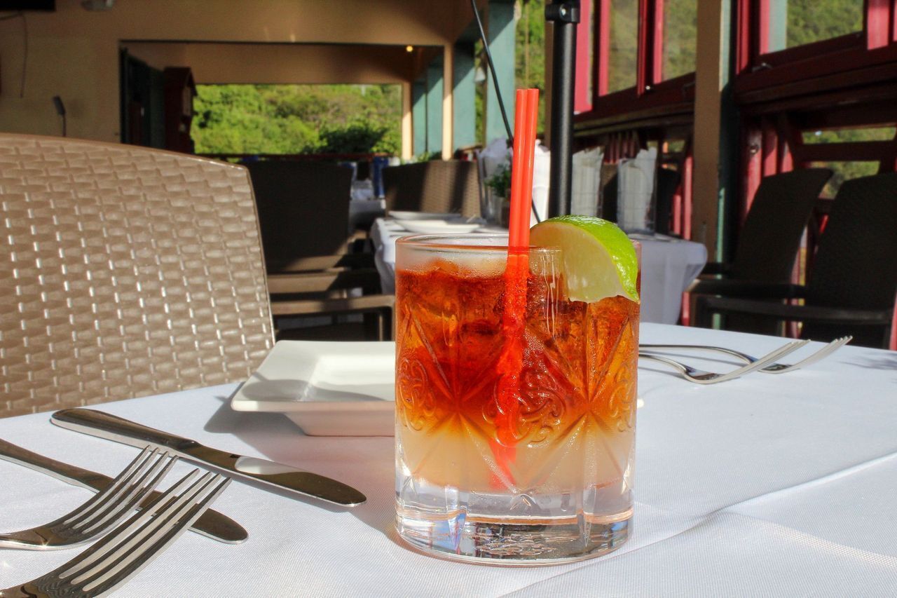 Une table avec un verre de thé glacé, une tranche de citron vert et une paille.