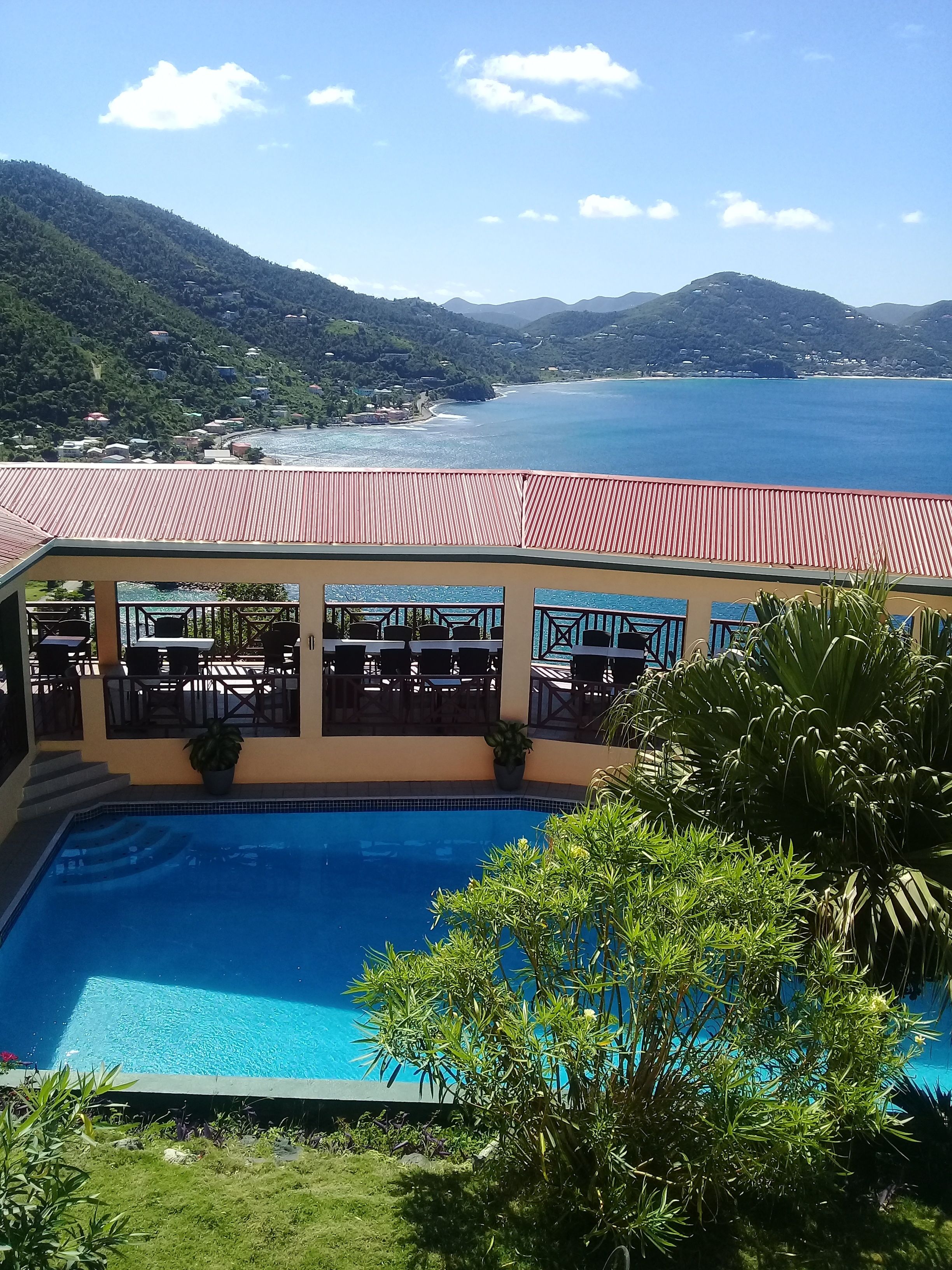 A poolside area with a view of the sea and mountains.