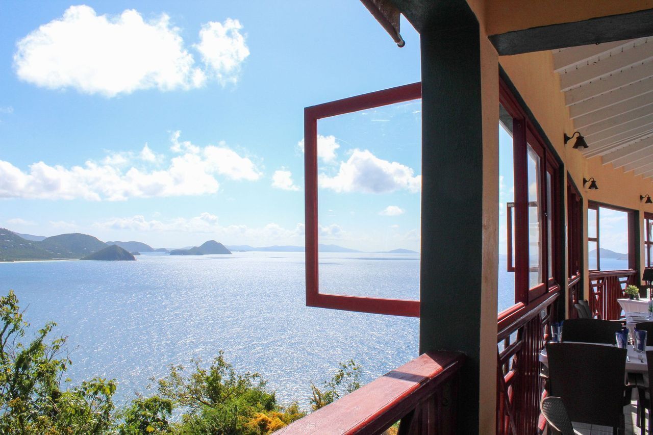Un restaurant offrant une vue sur une vaste étendue d’eau et sur des reliefs lointains.