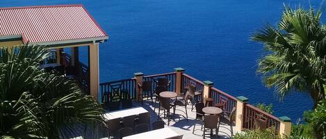 A terrace with outdoor seating overlooking a large body of water and distant landforms.