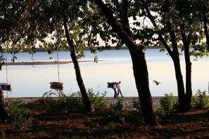 A lakeside scene with boats, trees, and people walking. - Hotel Zielony (Turawa)