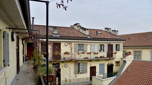 Um edifício de vários andares com varandas, telhado de telhas e uma viela estreita.