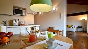 Cozinha moderna com micro-ondas, cafeteira e área de refeições com mesa posta para o café da manhã.
