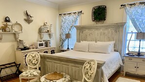 A bedroom with a bed, two chairs, a small table, a dresser, and a nightstand. - Bama Bed & Breakfast Campus (Tuscaloosa)