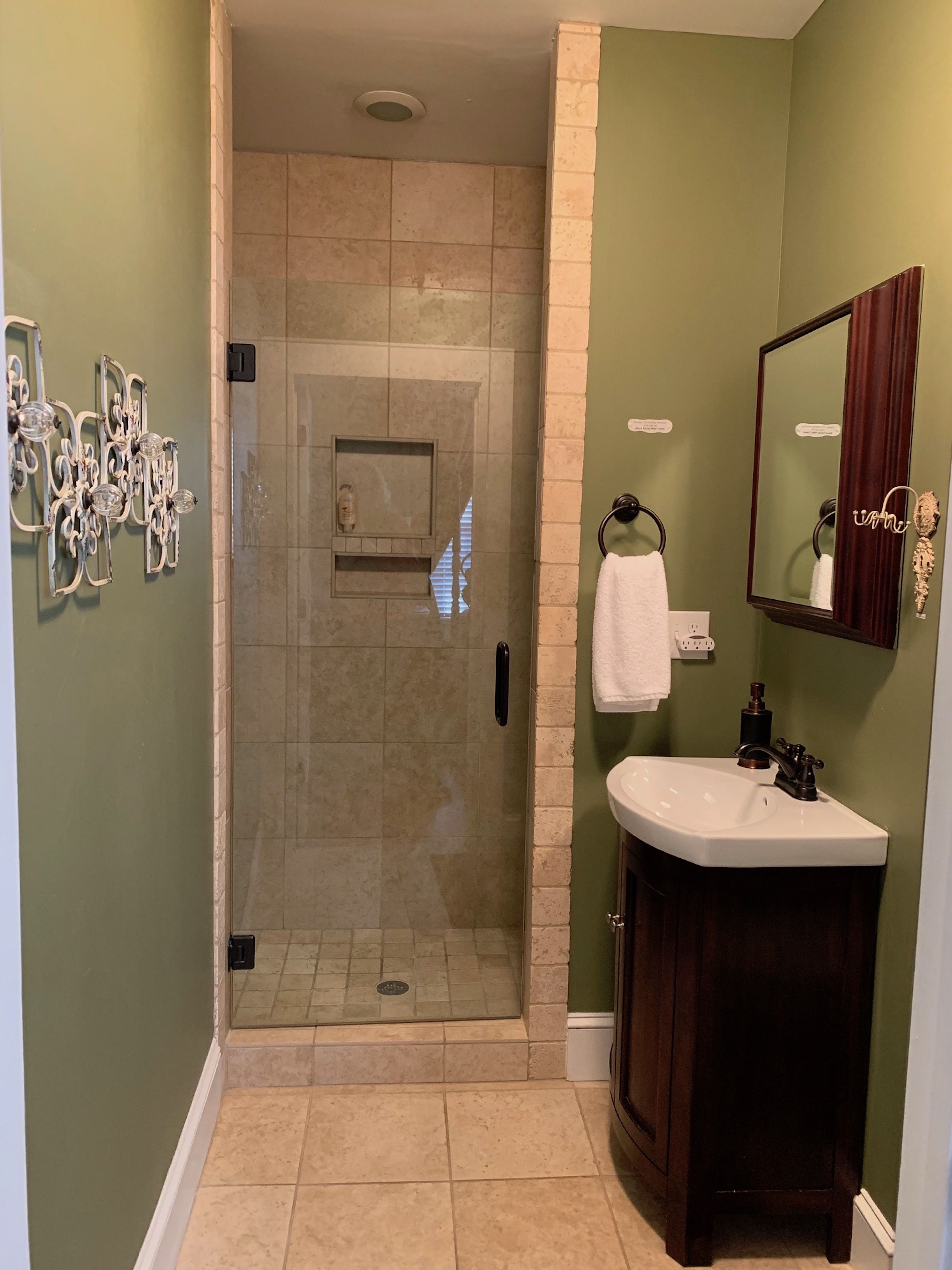A bathroom with a glass shower enclosure, a vanity with a sink, and a mirror.