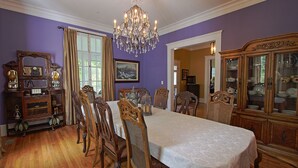 A dining room with a long table, chairs, a chandelier, and wooden cabinets. - Bama Bed & Breakfast Campus (Tuscaloosa)