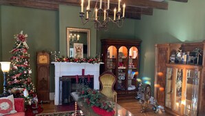 A cozy living room with a fireplace, a Christmas tree, and a dining table with a floral centerpiece. - Bama Bed & Breakfast Campus (Tuscaloosa)