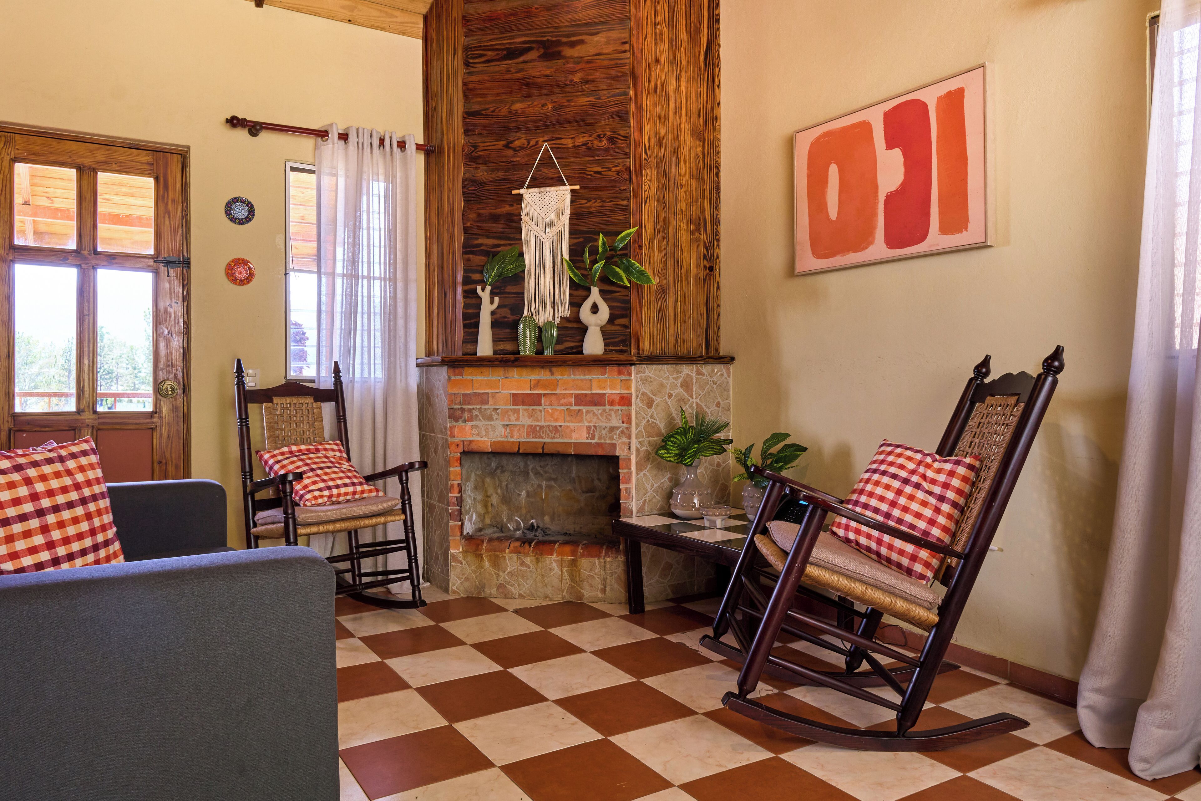 Una sala de estar acogedora con suelo a cuadros, una chimenea, sillones mecedores y un cuadro abstracto grande.