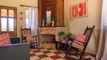 Una sala de estar acogedora con suelo a cuadros, una chimenea, sillones mecedores y un cuadro abstracto grande.
