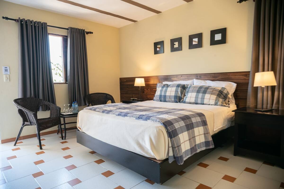 Een hotelkamer met een bed, twee stoelen, een tafel en een nachtkastje.