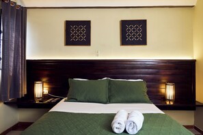 A neatly made bed with green bedding, two wall-mounted decorative panels, and bedside lamps. - Altocerro Villas Hotel & Camping (Constanza)