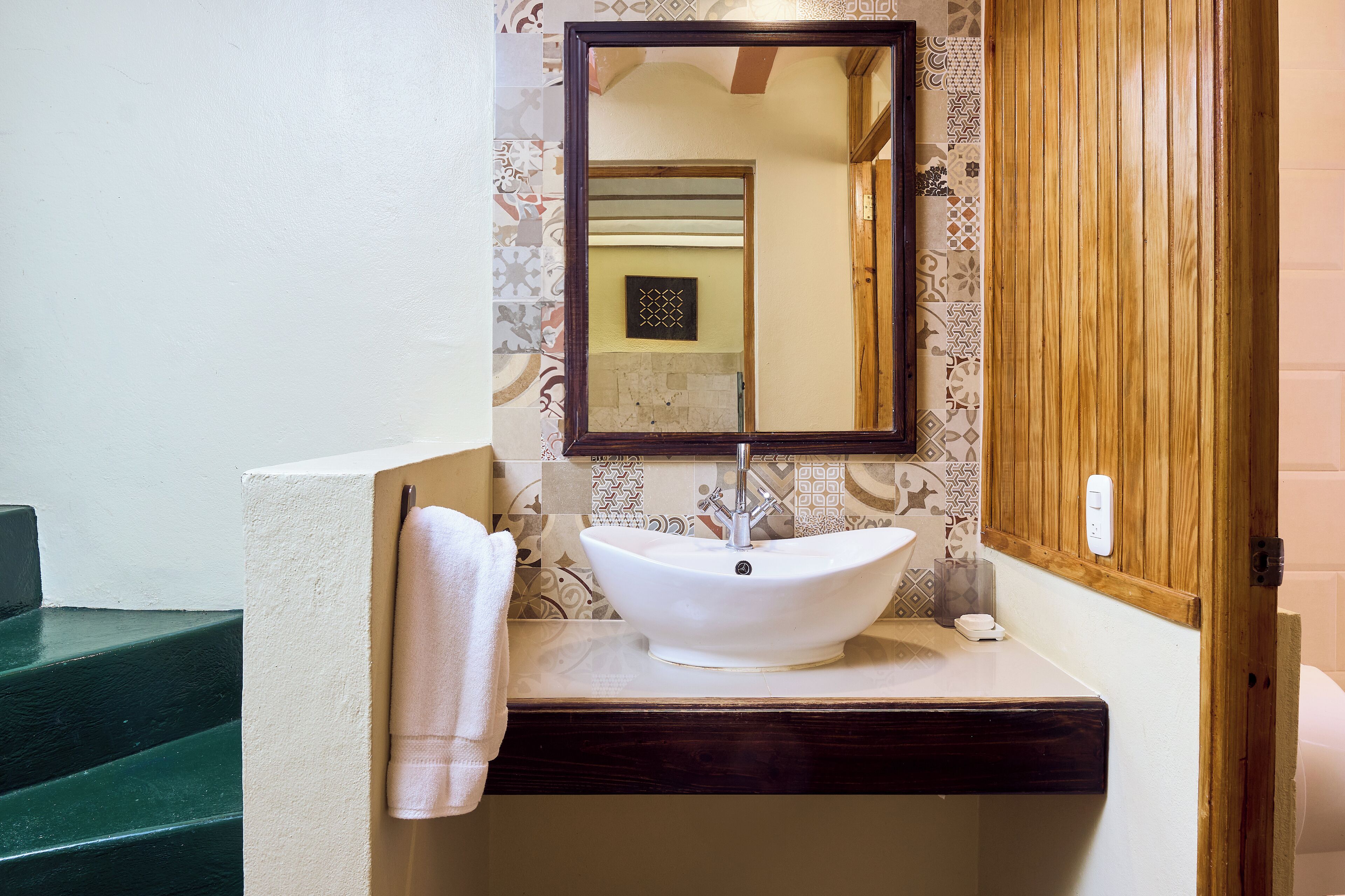 A bathroom with a white sink, a mirror, and a towel hanging on the wall.