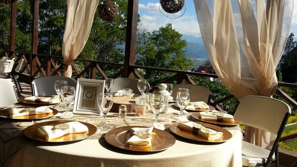 An outdoor dining area with tables set for a meal, featuring a scenic view of trees and mountains in the background. - Altocerro Villas Hotel & Camping (Constanza)
