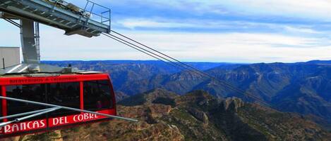 A cable car with "Bierveredos a Chimborazo" and "Rancas del Cobre" signage, offering a view of the Andes mountains.