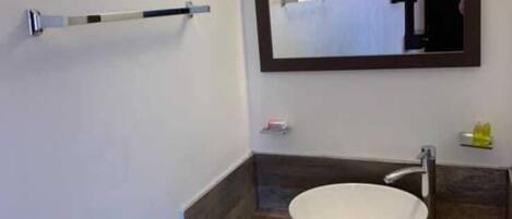 Un baño con un lavamanos blanco, un espejo y un perchero para toallas.