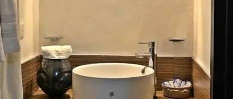 A bathroom with a round sink, a mirror, and a towel rack.